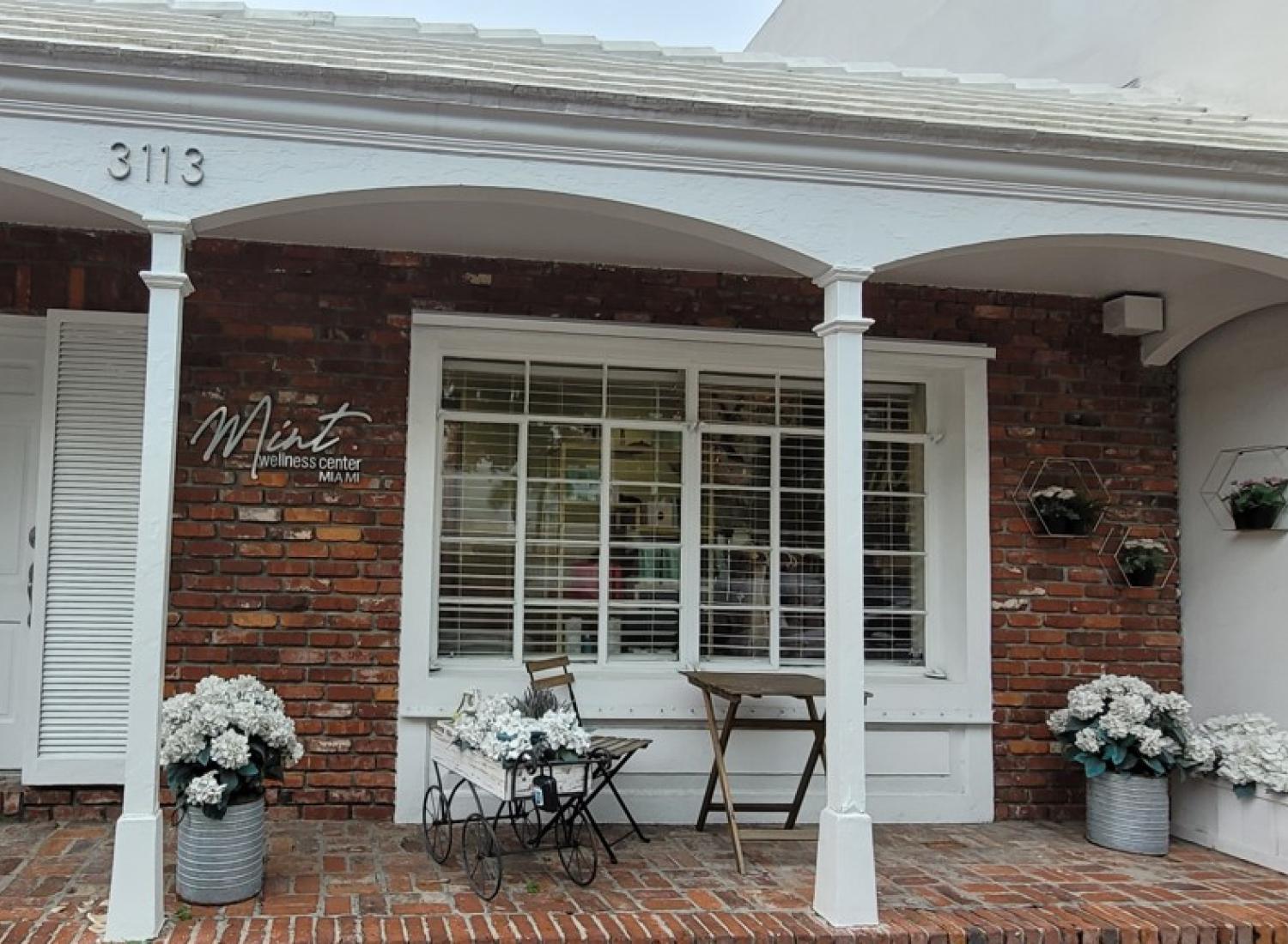 Brick house with white pillars and bouquets of white flowers on the porch