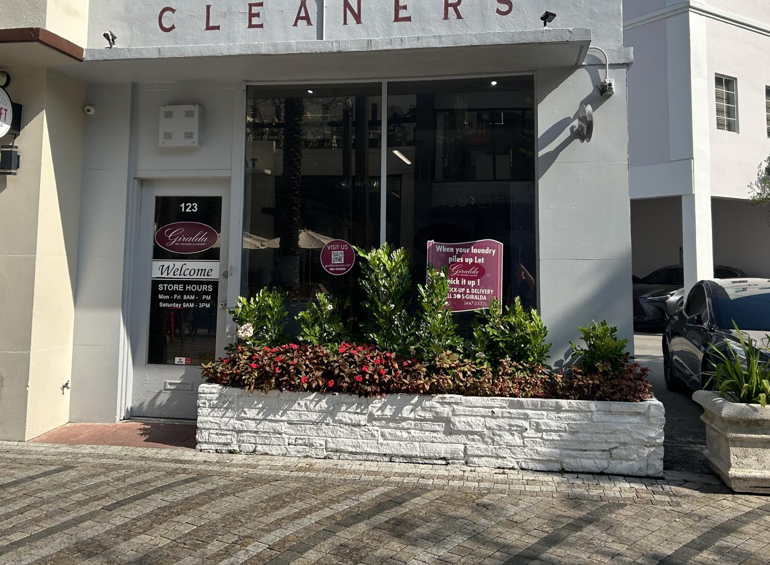 Exterior of Giralda Cleaners on Giralda Plaza with planters near the entrance.