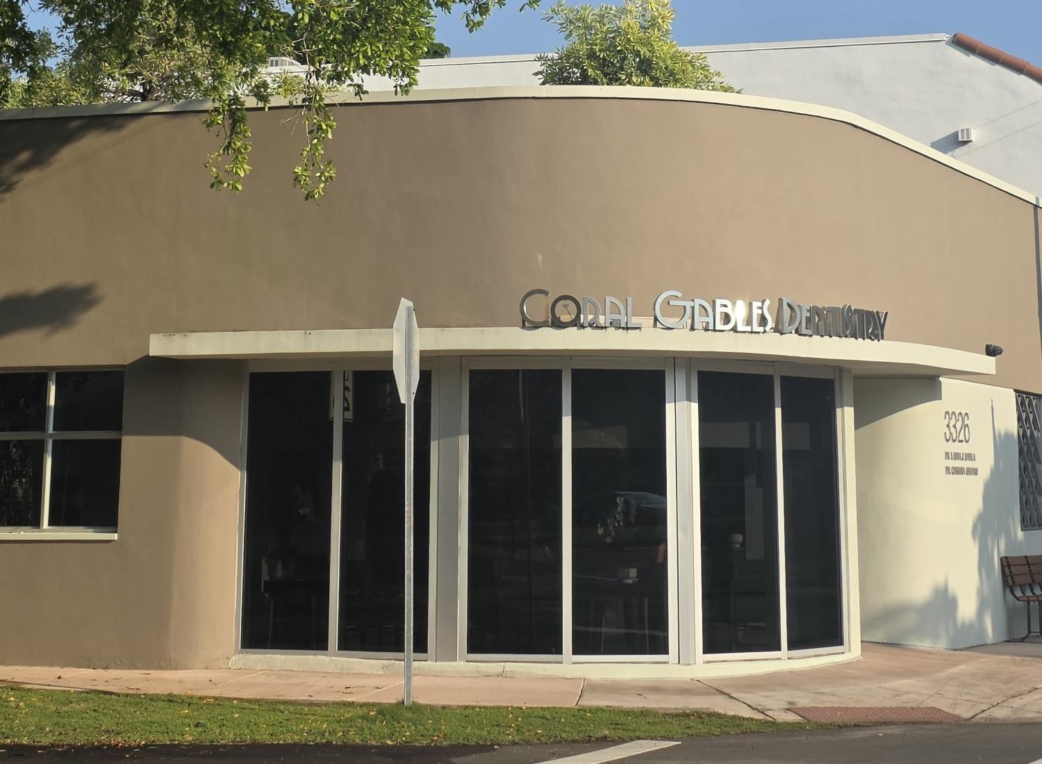 Beige exterior of Coral Gables Dentistry with large green tree on the side and blue sky overhead