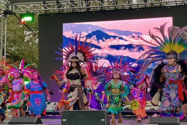 Children in colorful, purple and green and orange, costumes dance an Aztec dance
