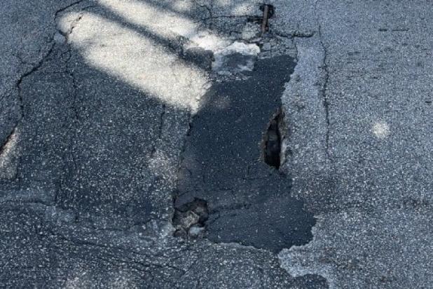 Pothole in the shade on the street with streaks of sunlight
