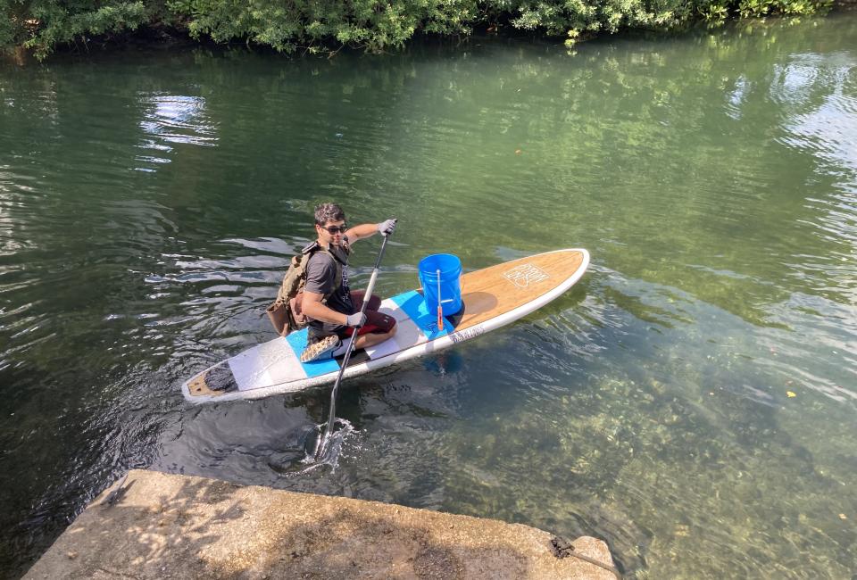 Young man participating in coastal cleanup via paddle board