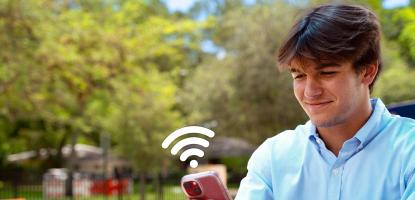 Young man accessing wi-fi in public park