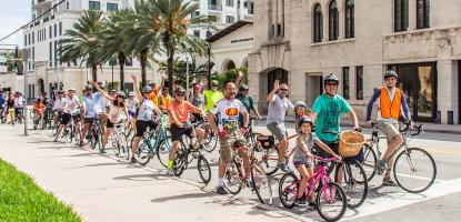 Group of cyclists wave in front of the Coral Gables Museum 