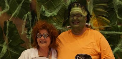 A woman and man dressed in costumes and holding signs