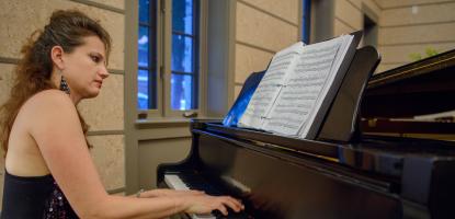 Side view of a woman in a black dress playing the piano