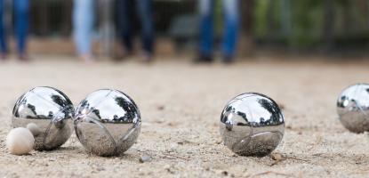 Four adults playing a game of pétanque