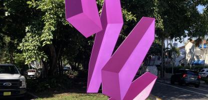 Violet, 3D blocks levitate in a patch of green grass in between two roads
