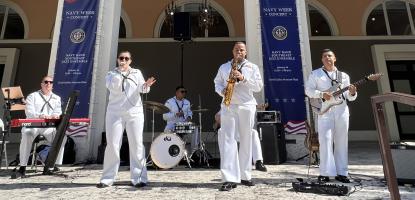 A band of 5 musicians play in front arches of a gallery. 