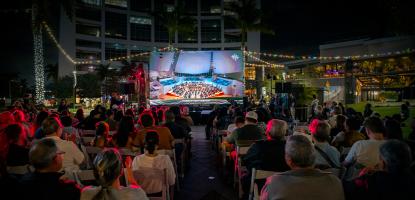 Audience looks at wall cast concert, projection wall with sound system