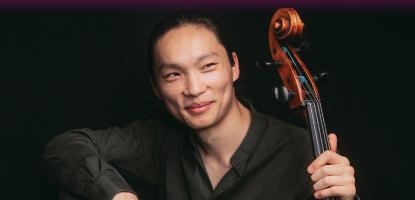 Leland Ko in long sleeved black shirt holding stringed instruments in front of black background
