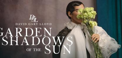 A man with flowers blocking his face in front of a wall and green curtain