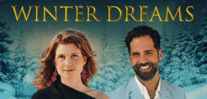 Woman in black and man in light blue suit smile in front of a snowy wonderland backdrop