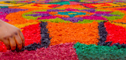 A hand over a colorful carpet with event details over it