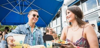 Two people smiling sitting beneath a Coyo Taco umbrella
