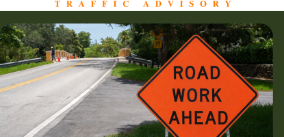 Orange Road work ahead sign next to a road on sunny day