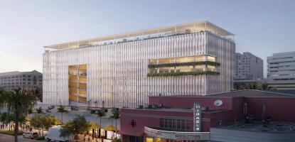 Mobility Hub rendering, large glass building with lights behind Miracle Mile at dusk