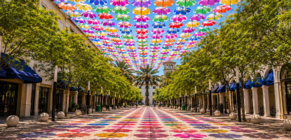 Colorful umbrellas cover the blue sky over Giralda Plaza with color shadows on the ground