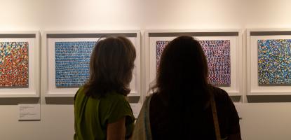 Two silhouetted women look at abstract art