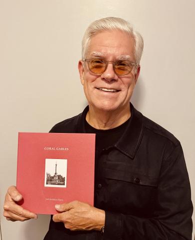 Jose Gelabert-Navia wearing black in a beige background holds up his book