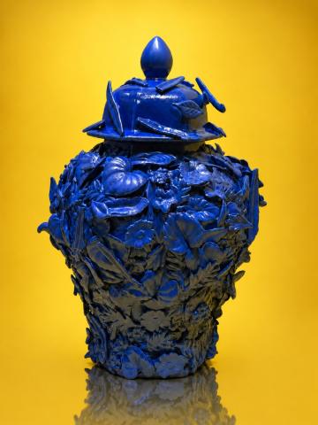 Blue lit sculpture backlit by a yellow background with darker gradients in the corners