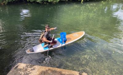 Young man participating in coastal cleanup via paddle board