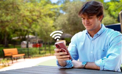 Young man accessing wi-fi in public park