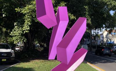 Violet, 3D blocks levitate in a patch of green grass in between two roads