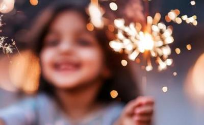 Out of focus, a little girl plays with sparklers