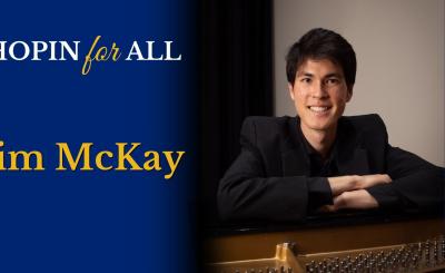 Tim McKay seated a closed piano, smiling