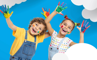 Two smiling children with painted hands against a bright blue sky with clouds 