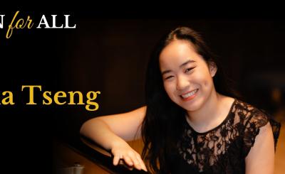 Karina Tseng smiling in a black dress with a black background behind her