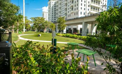 Green space with train pass and large white building and blue sky in the background