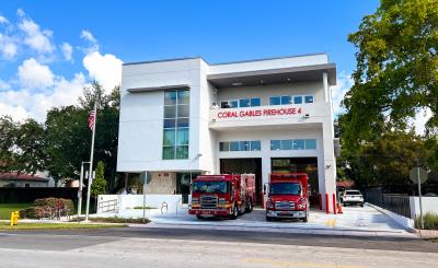 White, modern Fire House 4 with two red fire trucks in the driveway with blue sky in the background