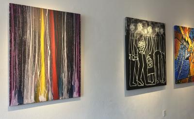 3 different paintings hanging on white wall, abstract yellow and red, line drawings, and colorful shapes