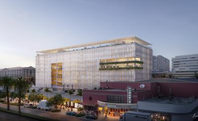 Mobility Hub rendering, large glass building with lights behind Miracle Mile at dusk