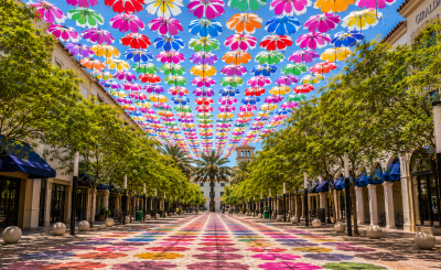 Colorful umbrellas cover the blue sky over Giralda Plaza with color shadows on the ground