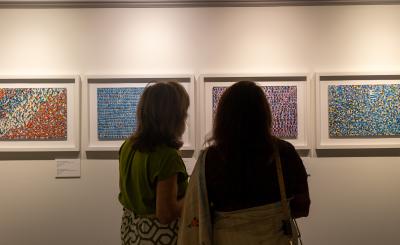 Two silhouetted women look at abstract art