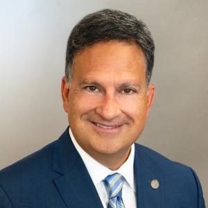 Commissioner Richard D. Lara's headshot, smiling in a suit with white to beige gradient background