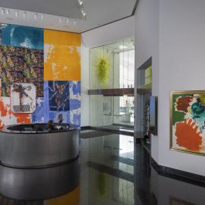 Lobby with colorful abstract murals and paintings, featuring bright orange, blue, yellow, and patterned panels behind a circular reception desk.