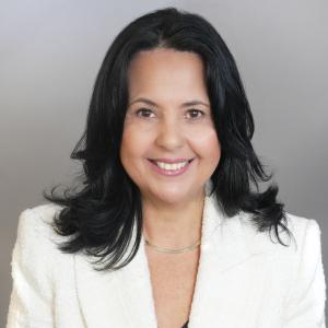 Lina Santiago in white suit jacket smiling
