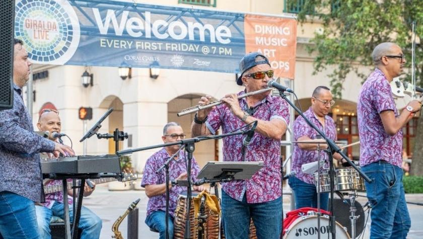 Band plays instruments on stage in matching violet pattern shirts