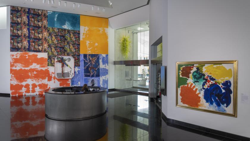 Lobby with colorful abstract murals and paintings, featuring bright orange, blue, yellow, and patterned panels behind a circular reception desk.